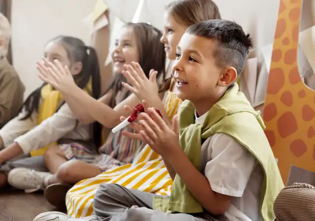 Children sitting on the floor clapping.